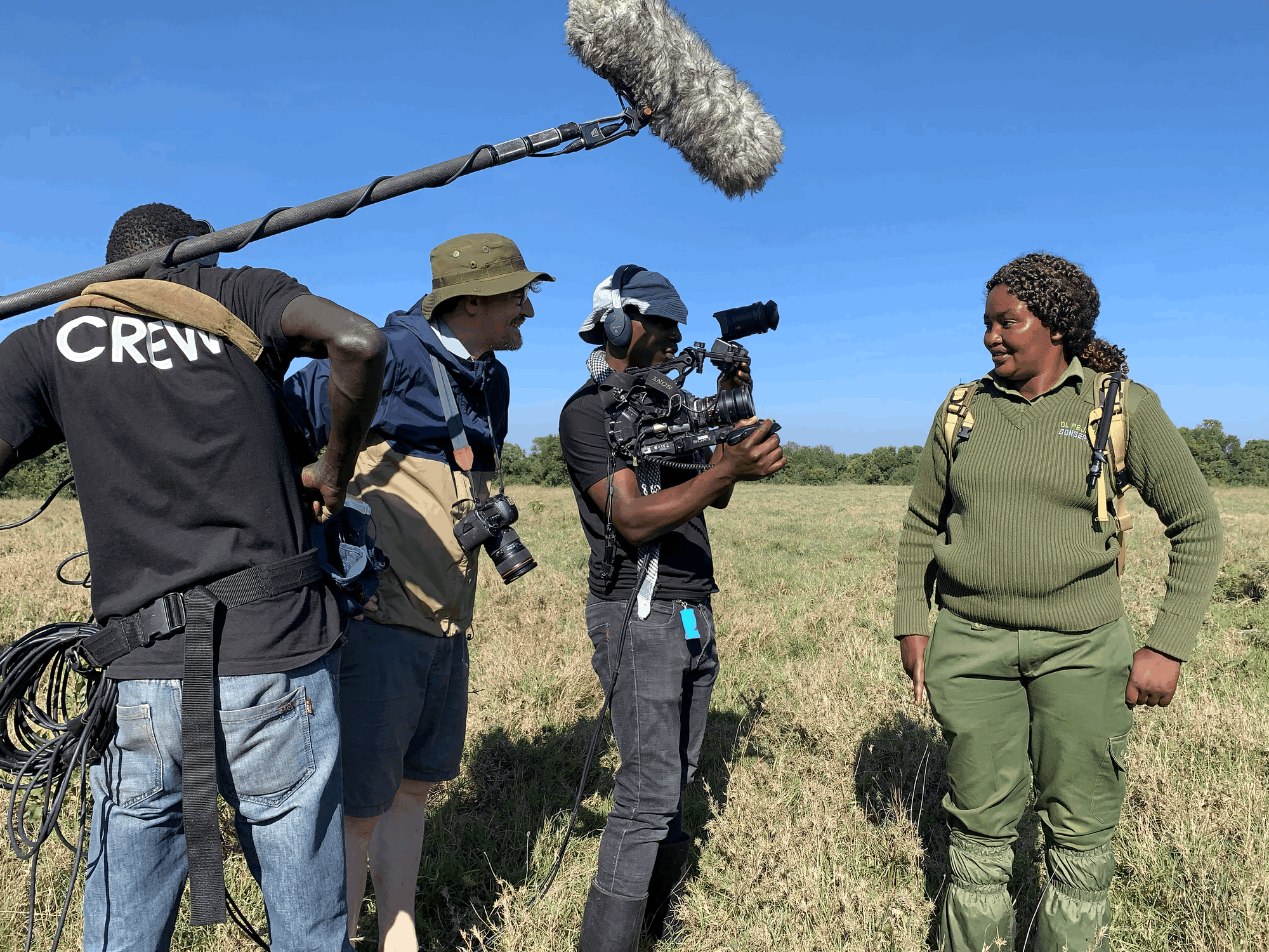 African camera crew filming a ranger in the savanna